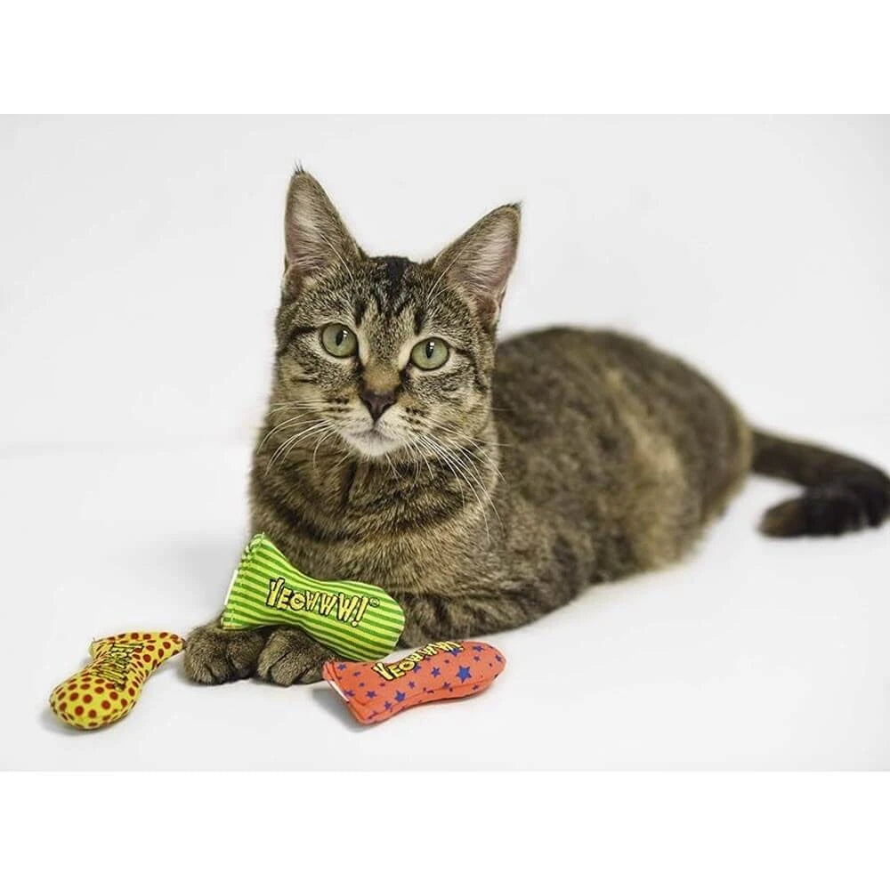 Cat lying on a white surface with two toys beside it yeowww stinkies toys